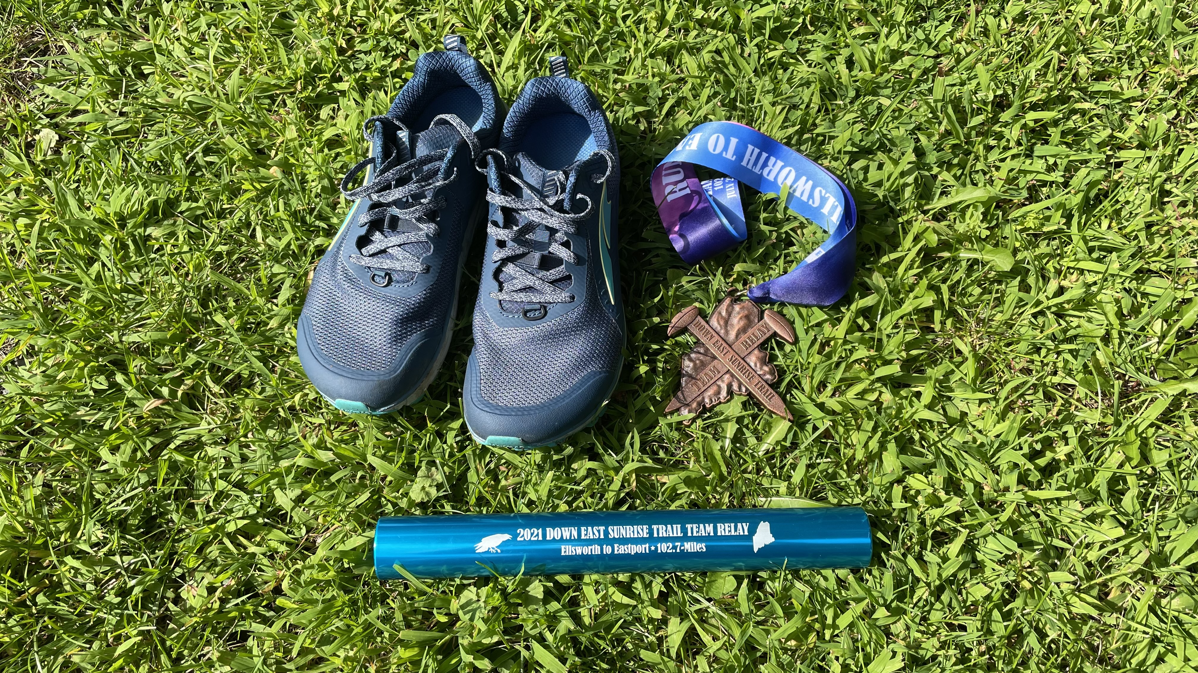 My trail runners, medal and the team's relay baton.